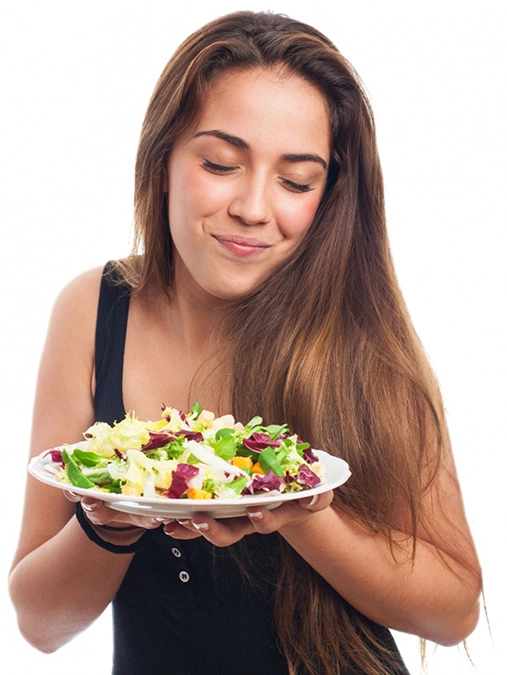 Moça jovem com prato de comida nas mãos e uma expressão de satisfação ao sentir o aroma do alimento. Moça jovem com prato de comida nas mãos e uma expressão de satisfação ao sentir o aroma do alimento.